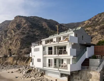 Beachfront home exterior below coastal hills